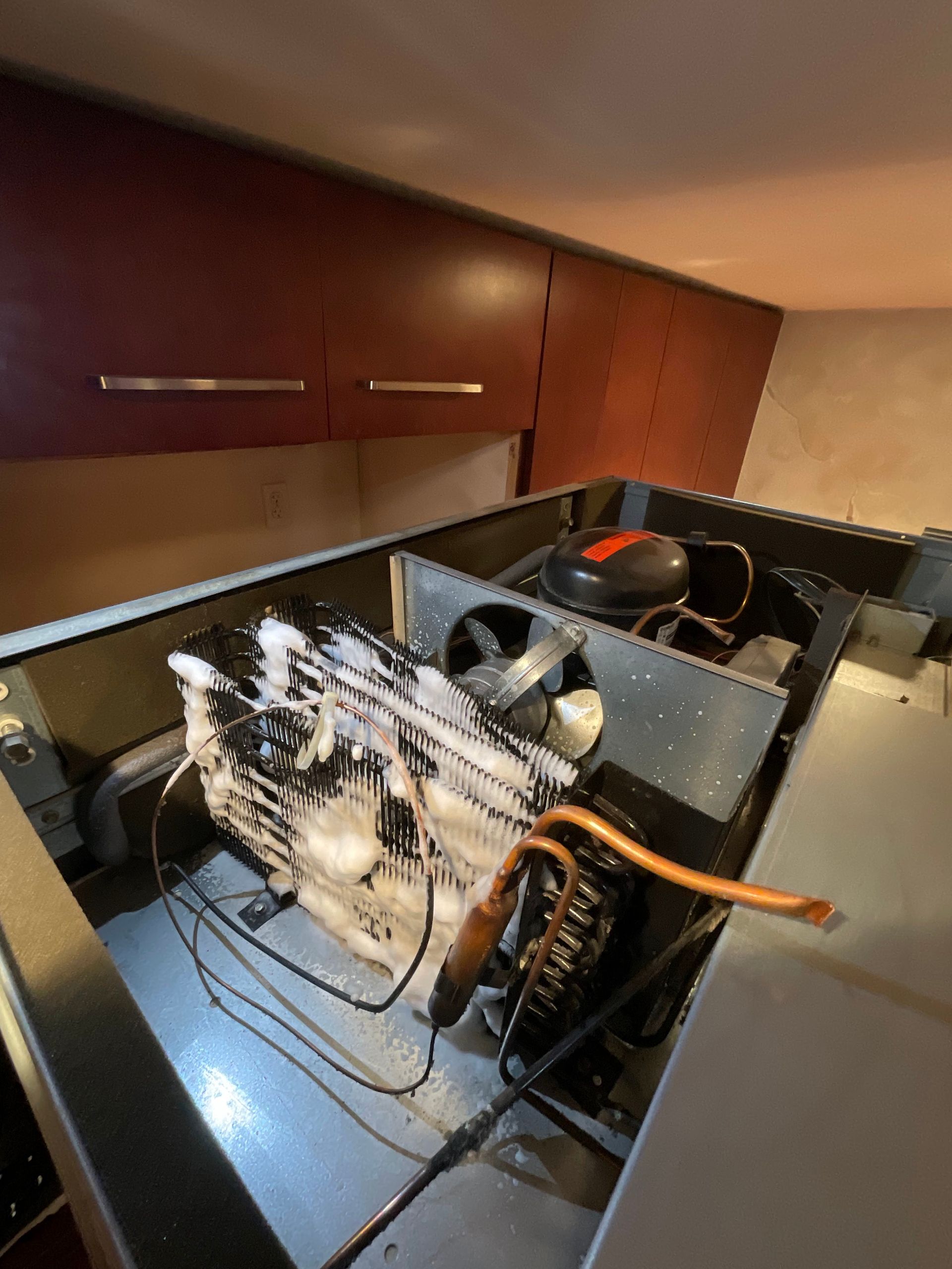 The inside of a refrigerator with a lot of wires coming out of it