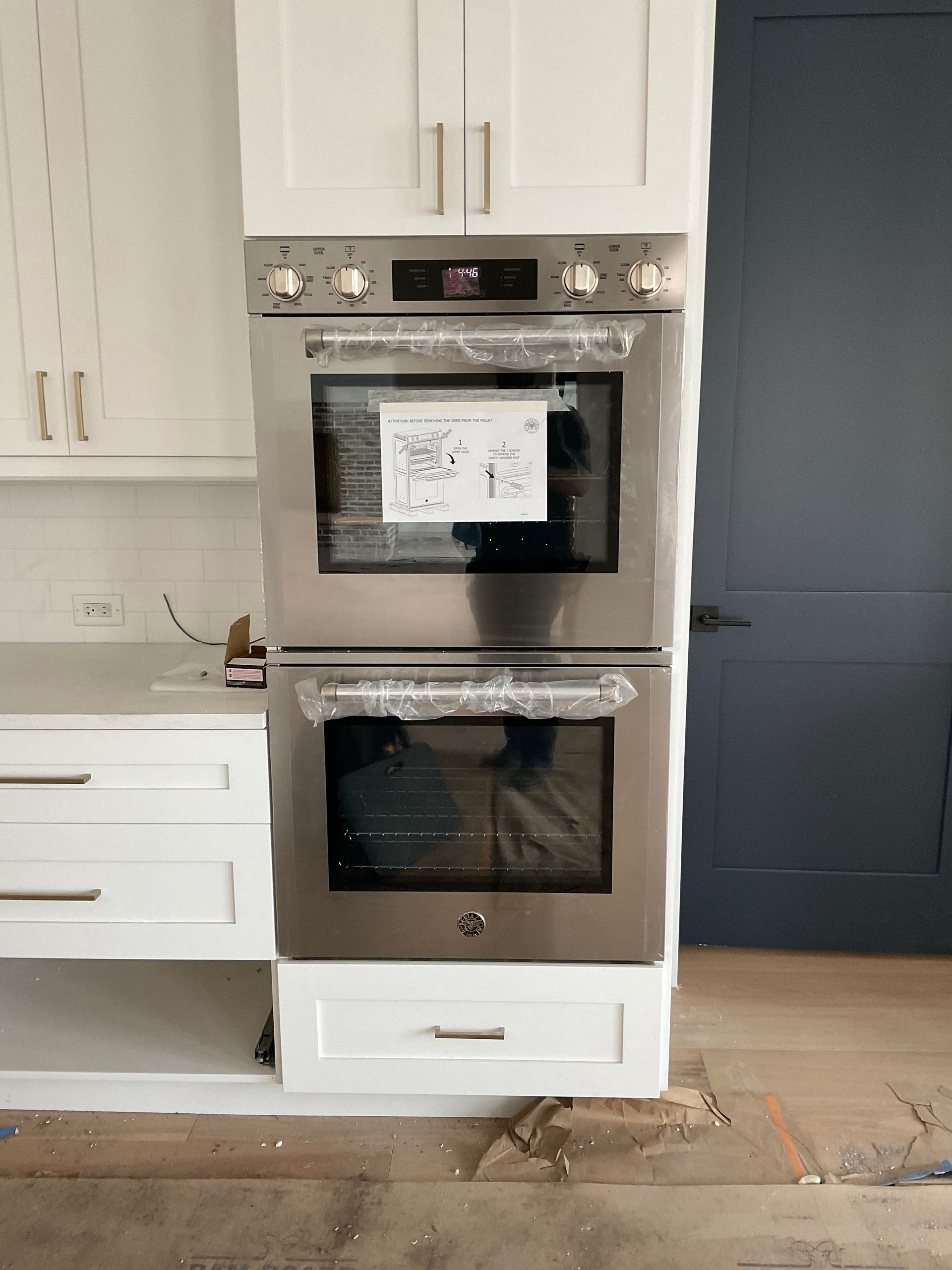 A stainless steel double oven in a kitchen with white cabinets