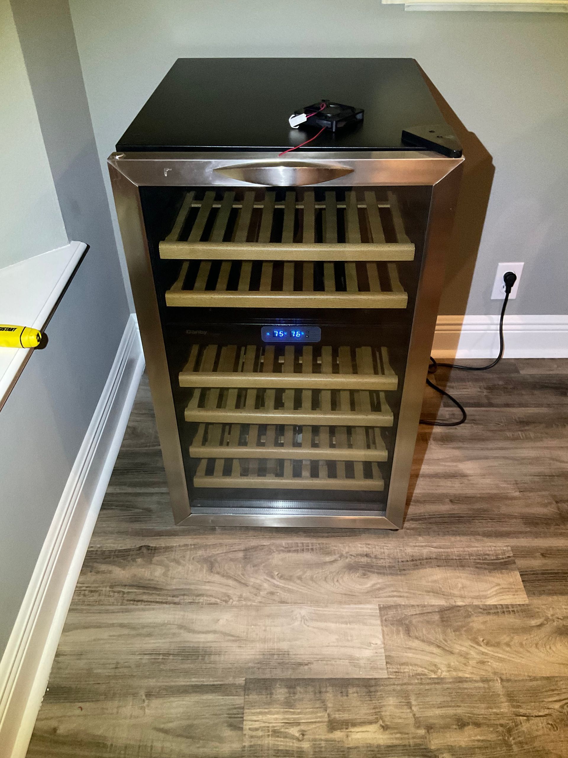A wine cooler is sitting on a wooden floor in a room.