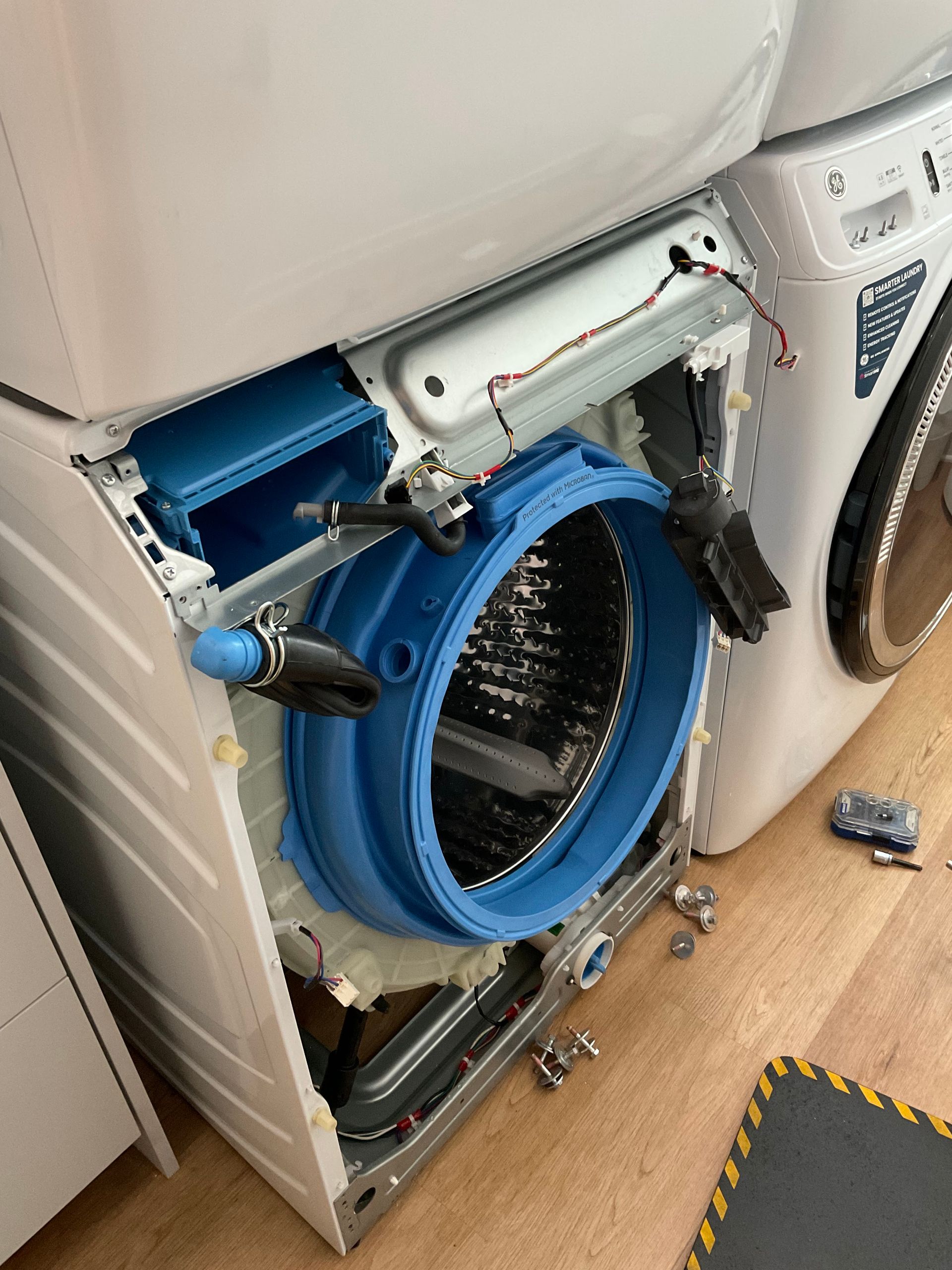 A washer and dryer are sitting on top of each other on a wooden floor.