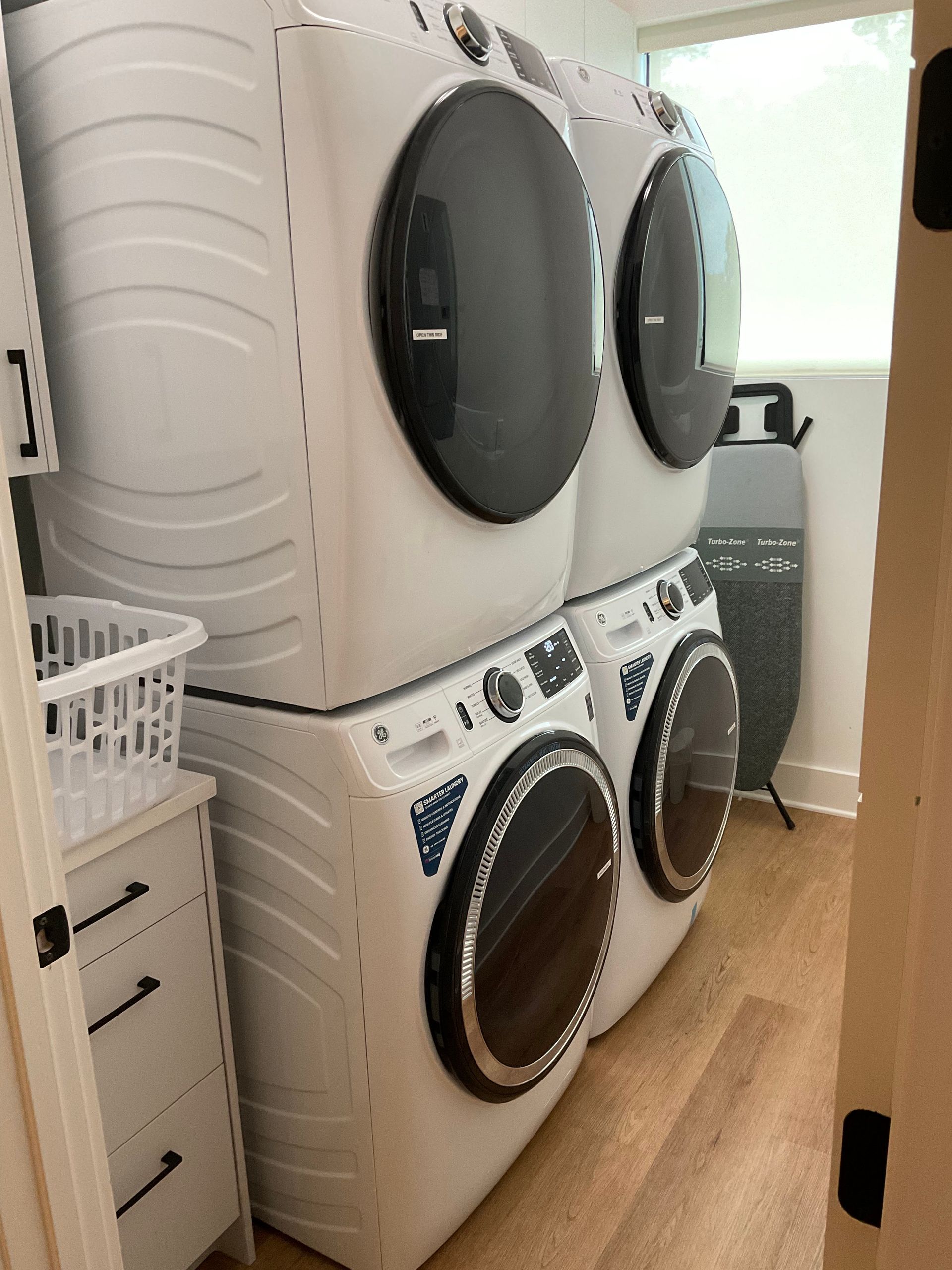Two washers and dryers are stacked on top of each other in a laundry room.