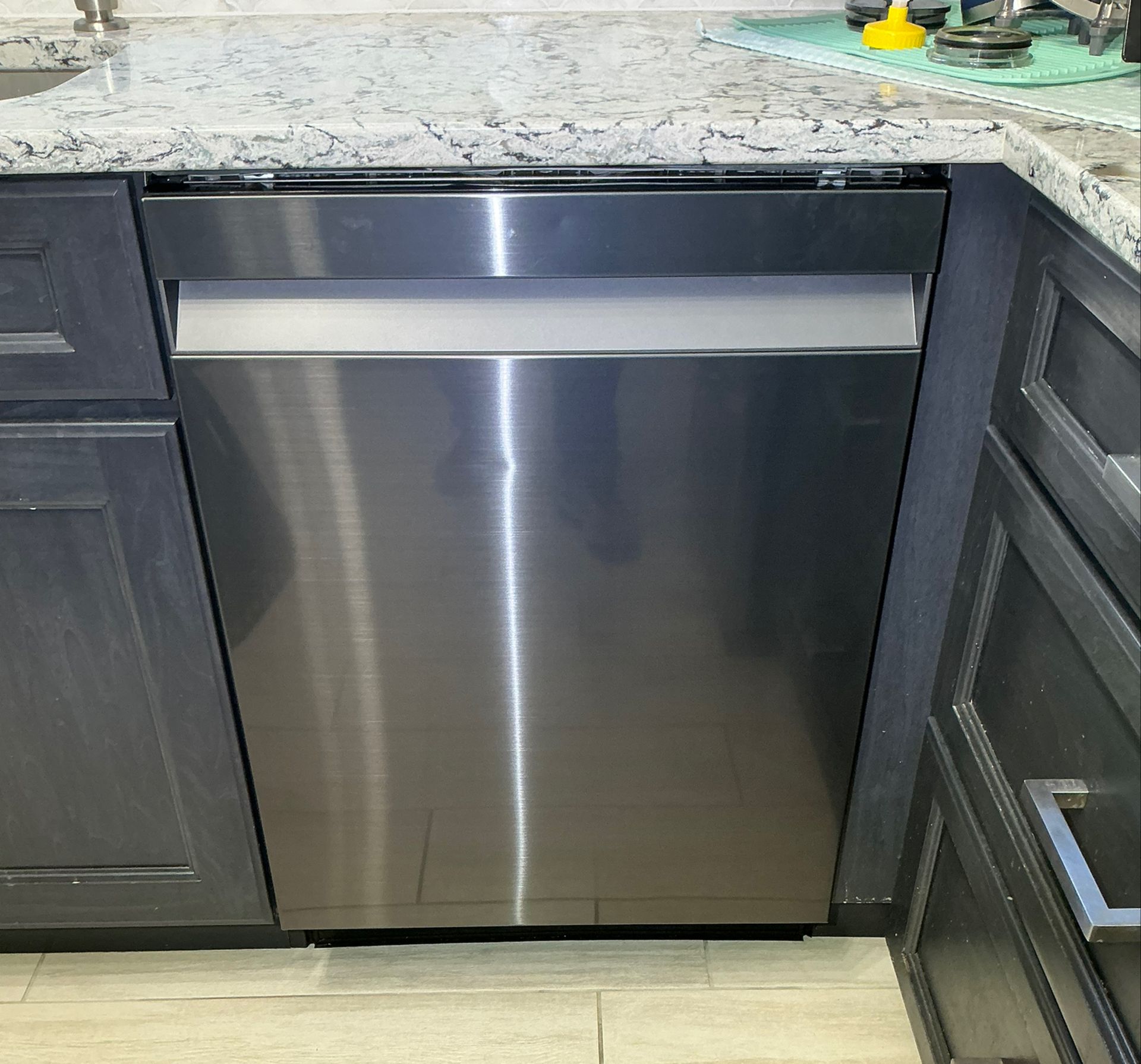 A stainless steel dishwasher is sitting under a granite counter top in a kitchen.