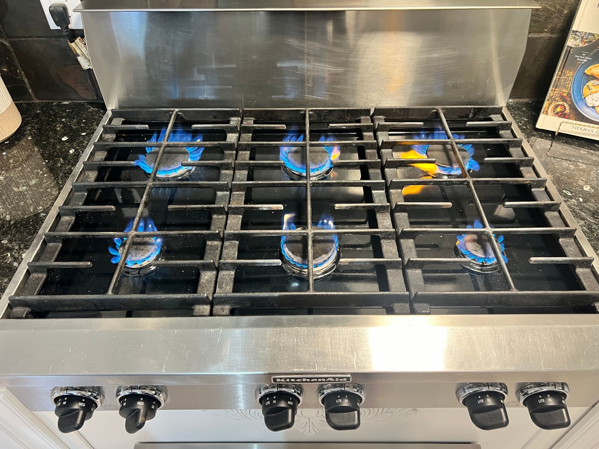 A stainless steel gas stove with blue flames coming out of the burners.