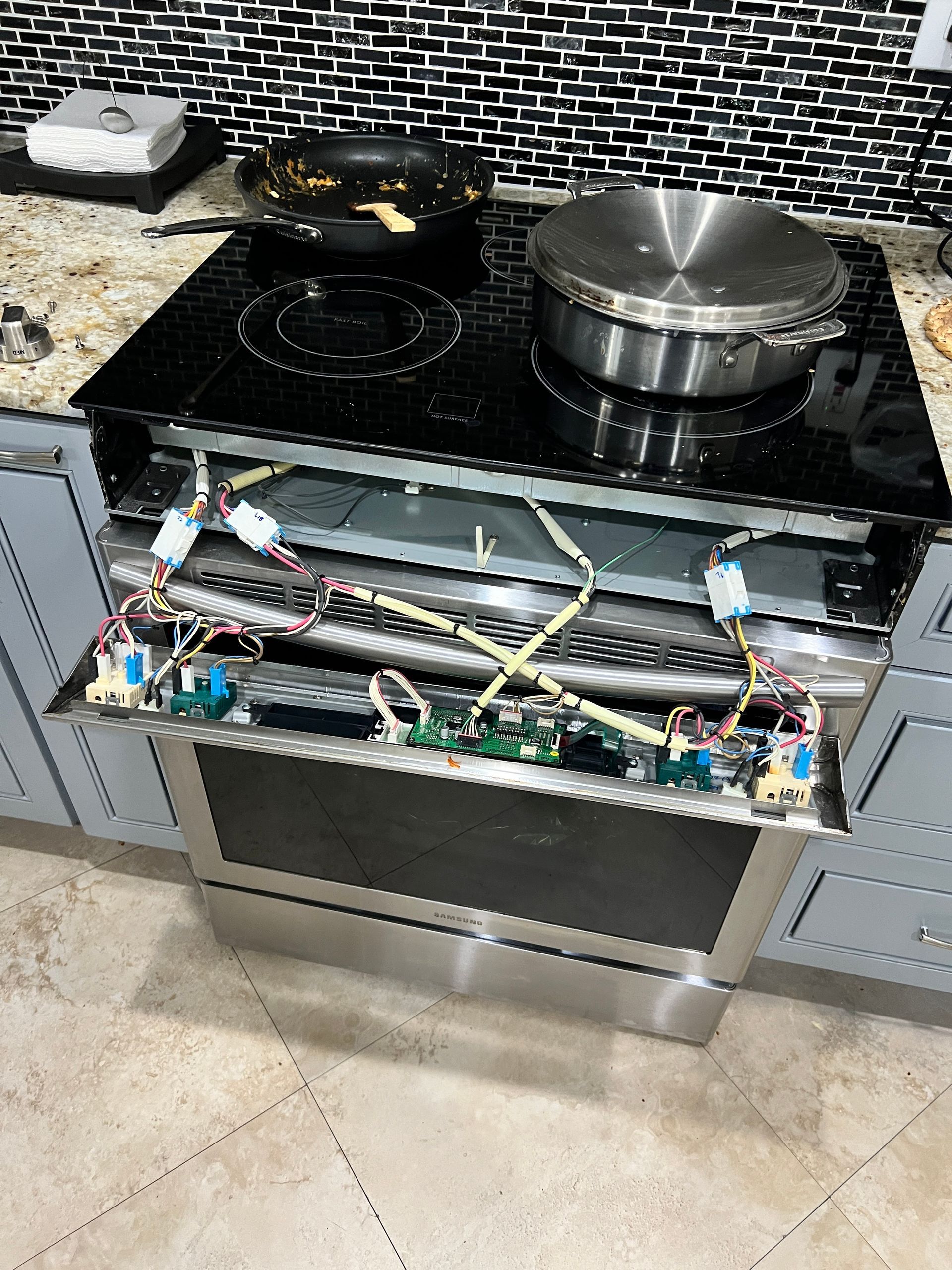 A stove with the door open and a pot on top of it in a kitchen.