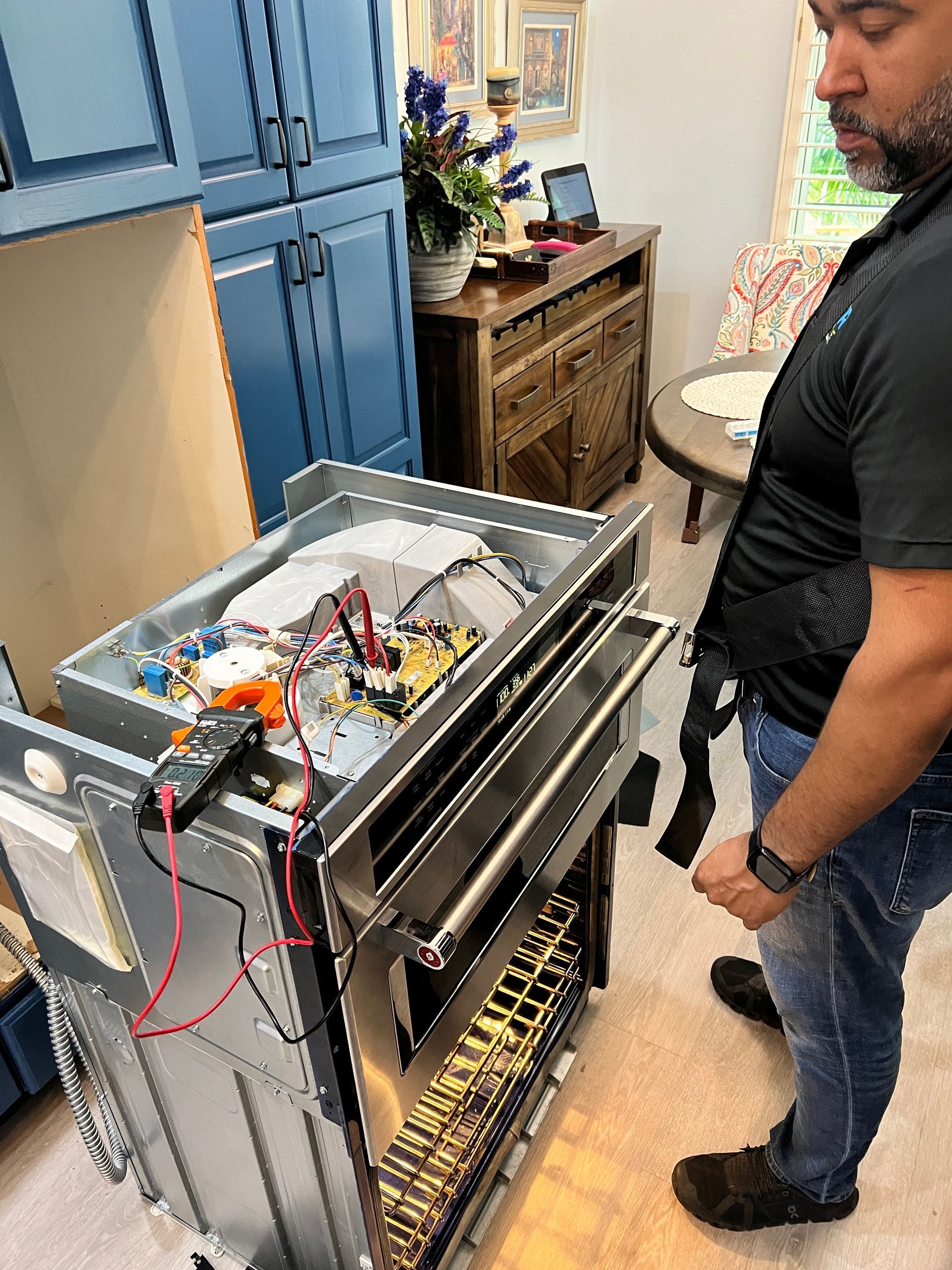 A man is working on a dishwasher in a kitchen.
