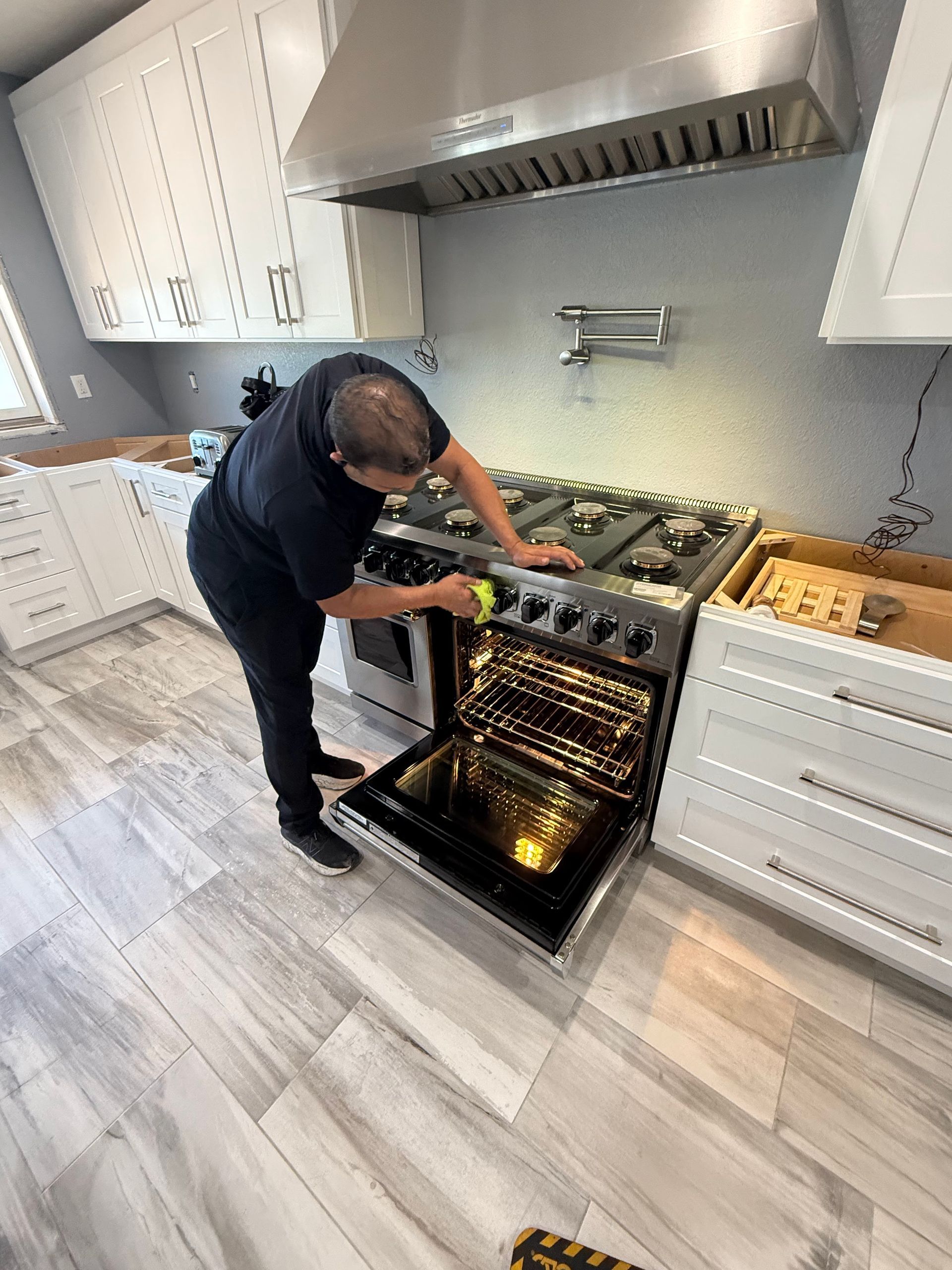 A man is working on a stove in a kitchen.