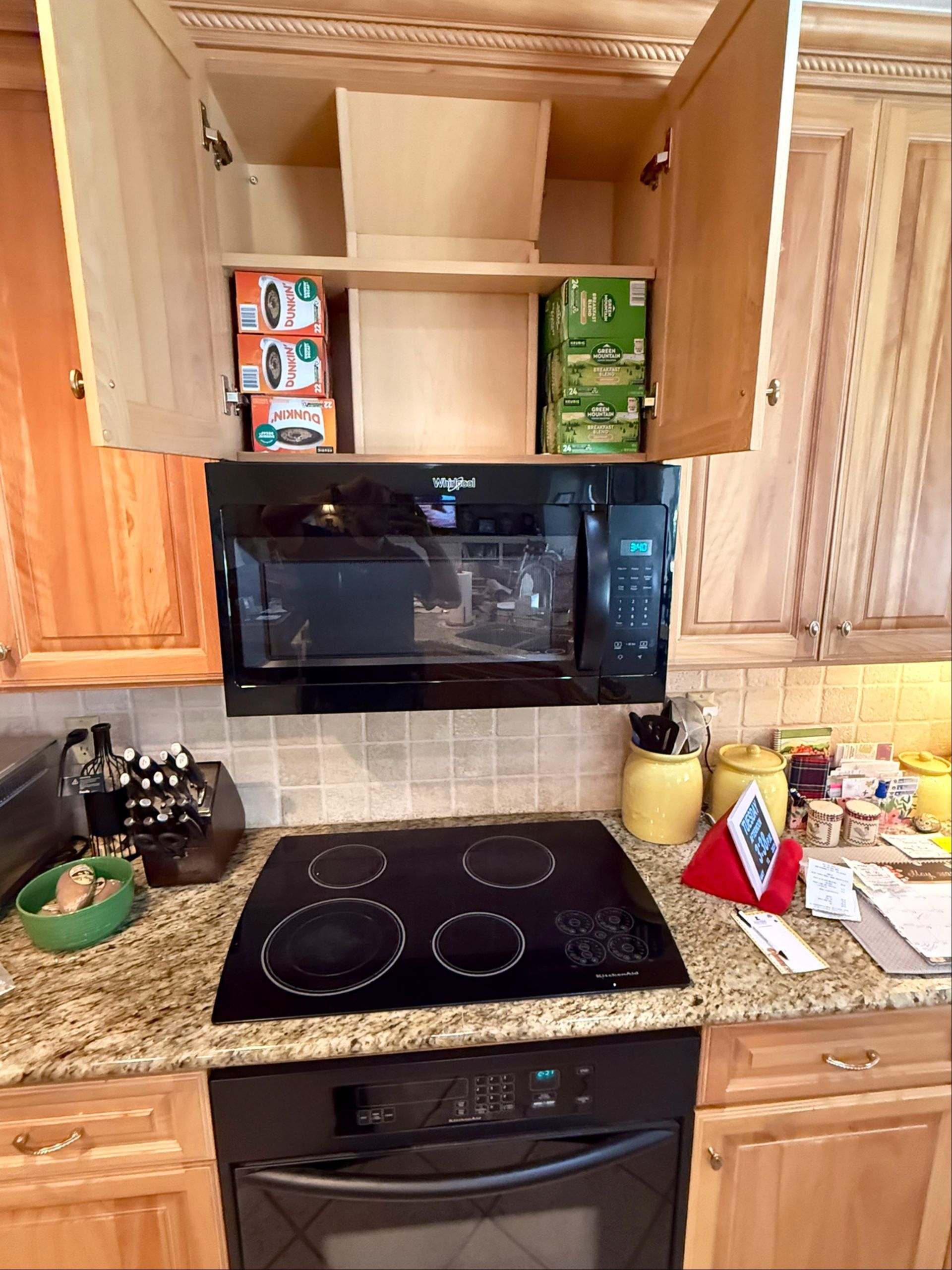 A kitchen with a stove top oven , microwave , and cabinets.