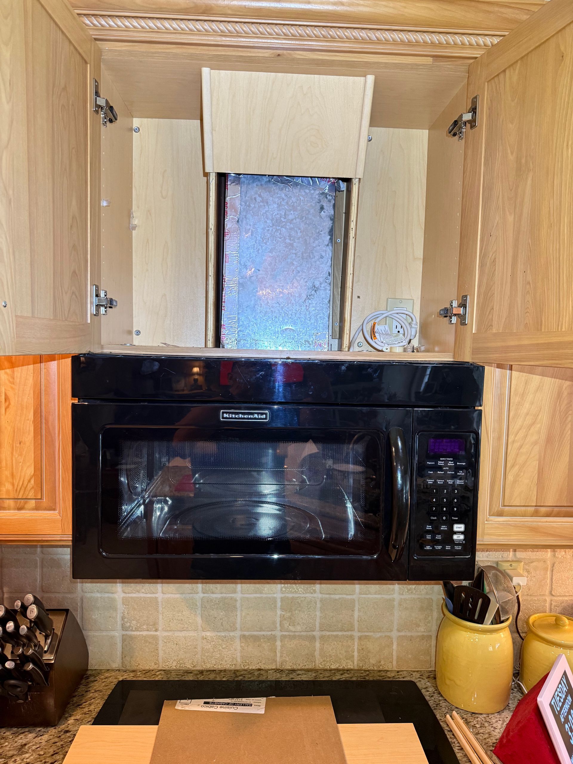 A kitchen with a microwave and cabinets open