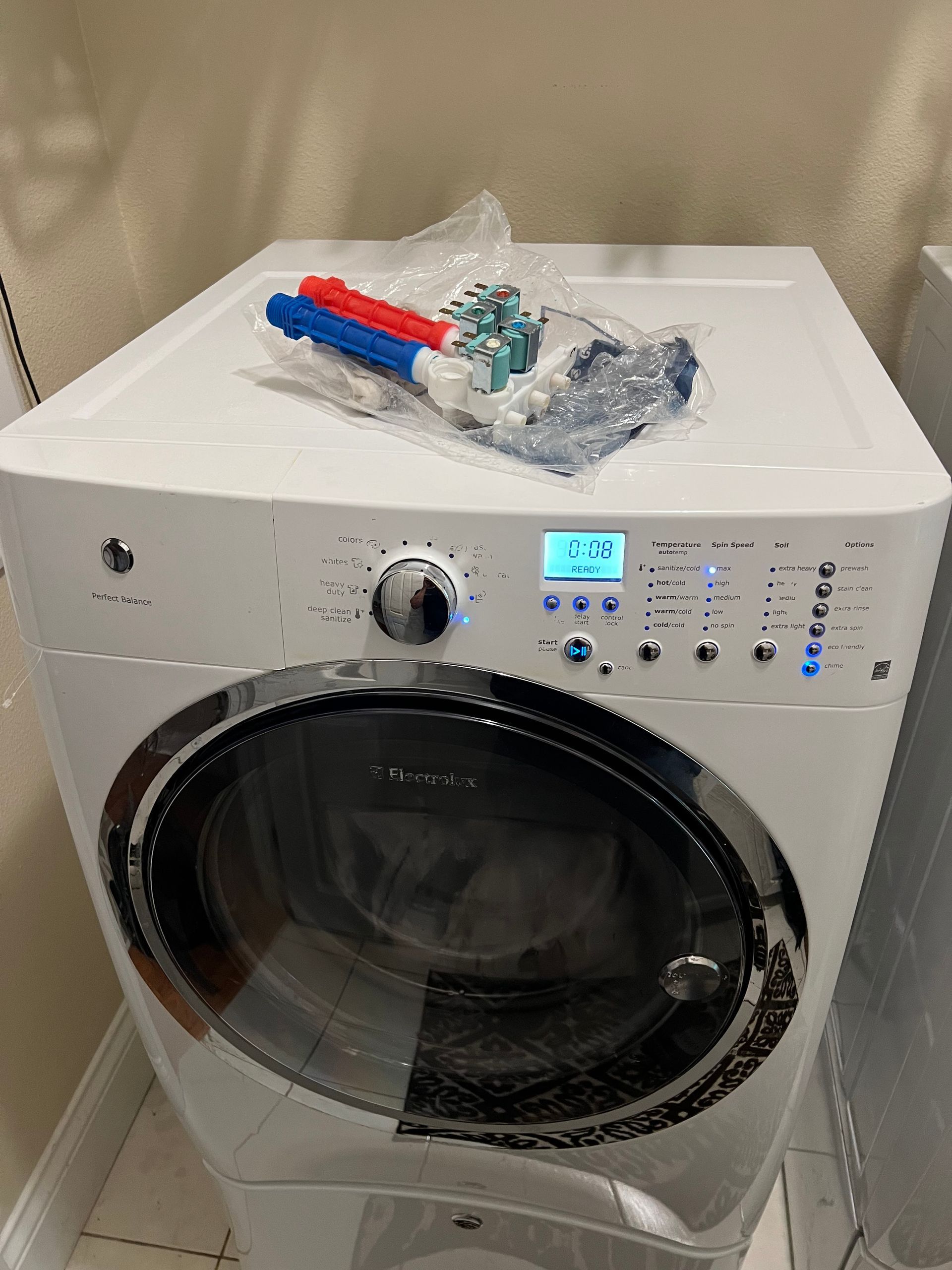 A white washing machine with a bag of markers on top of it.