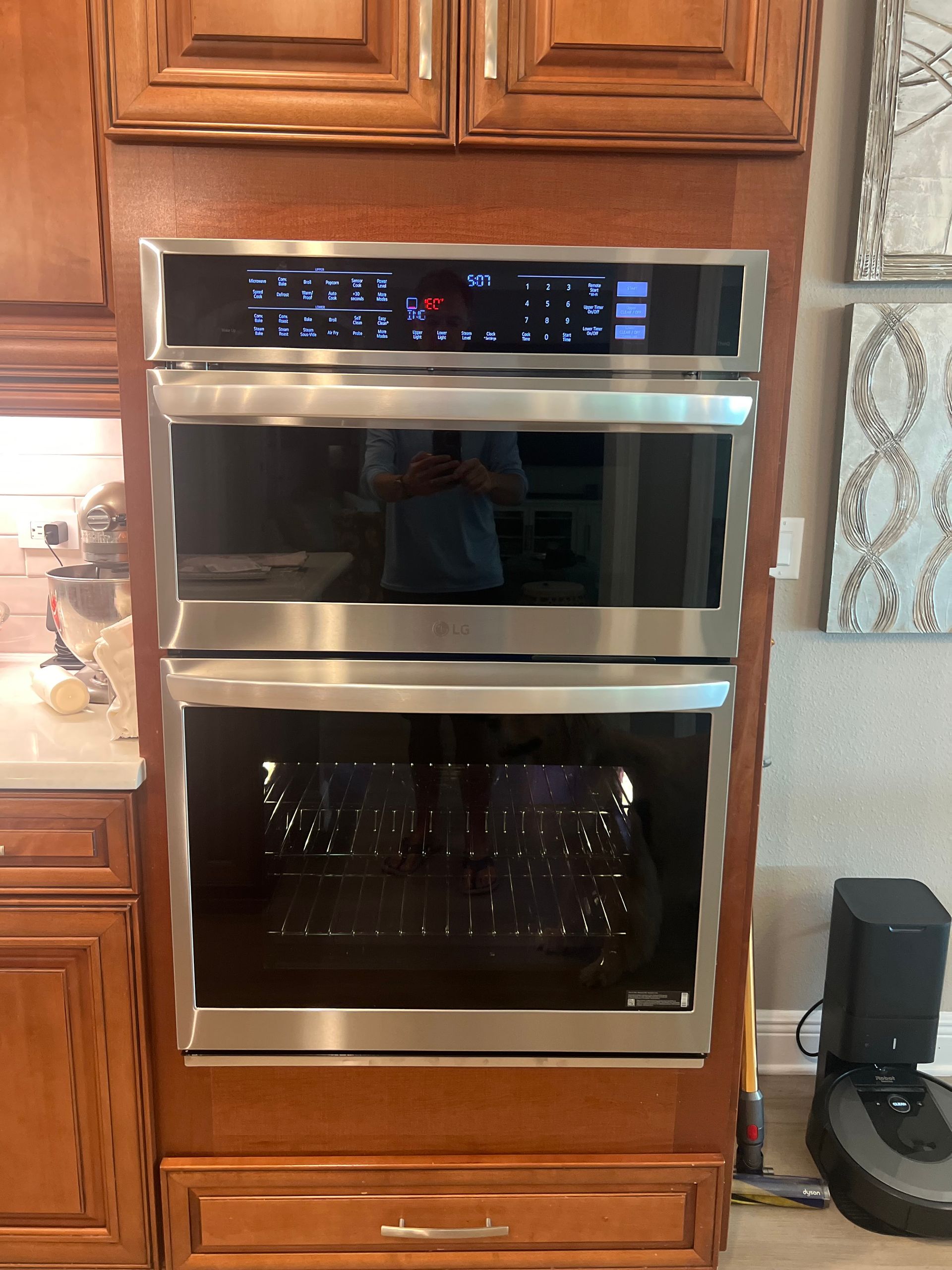 A double oven is sitting on top of a wooden cabinet in a kitchen.