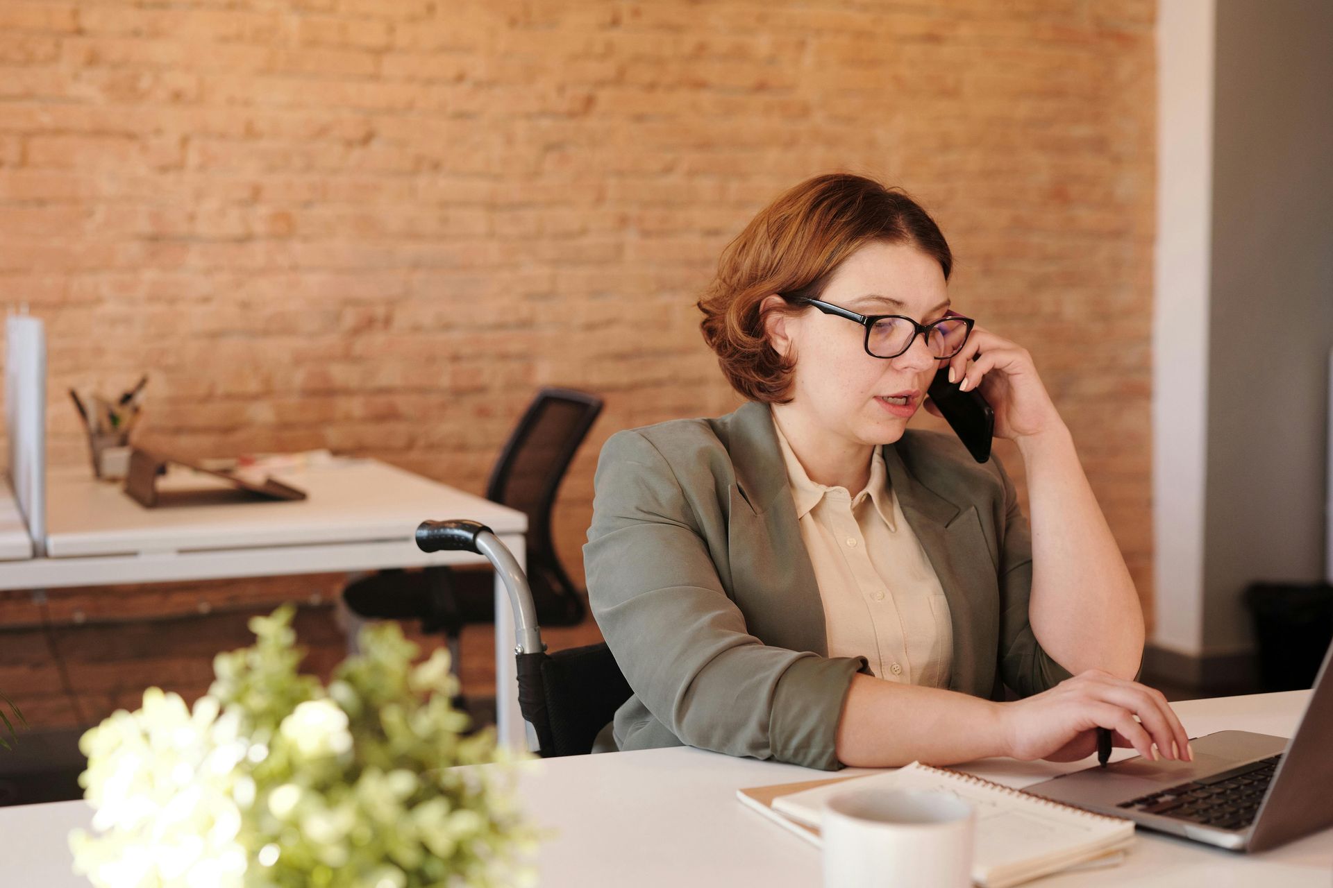 Person working on a laptop while talking on the phone in an office setting