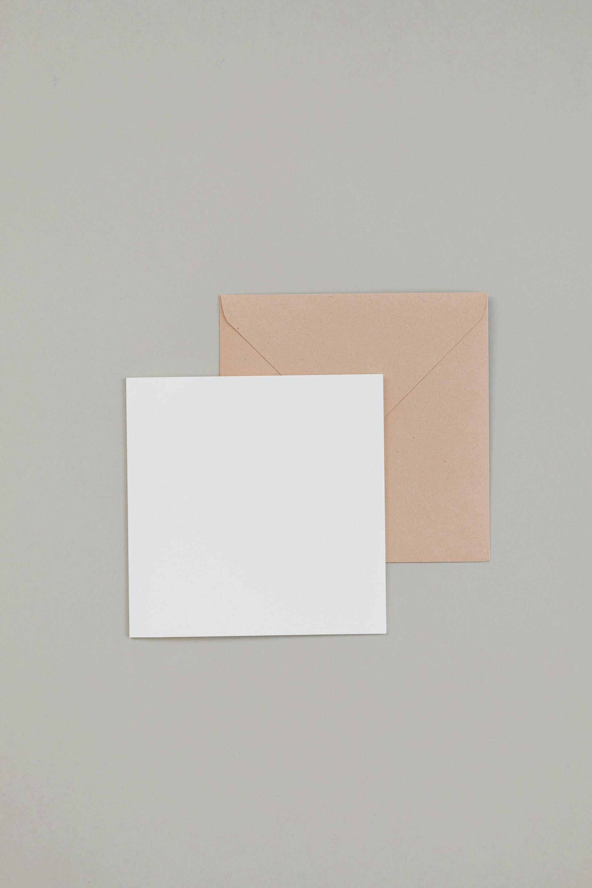 White square paper overlapping a tan square on a light gray background