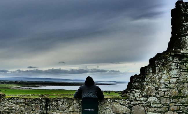 A person standing on a stone wall overlooking  Easkey left 