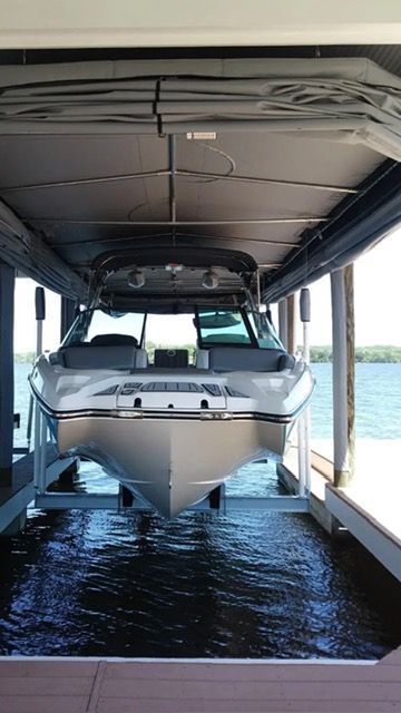 White boat docked in a covered slip over dark water, viewed from the bow
