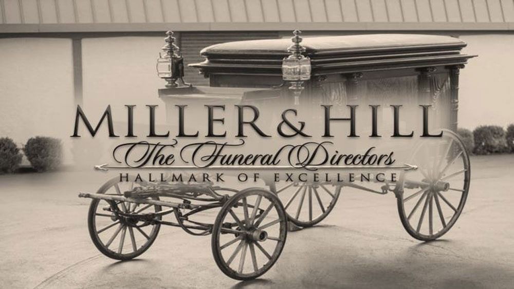 Sepia-toned funeral hearse with large wheels and “MILLER & HILL Funeral Directors” text backdrop.