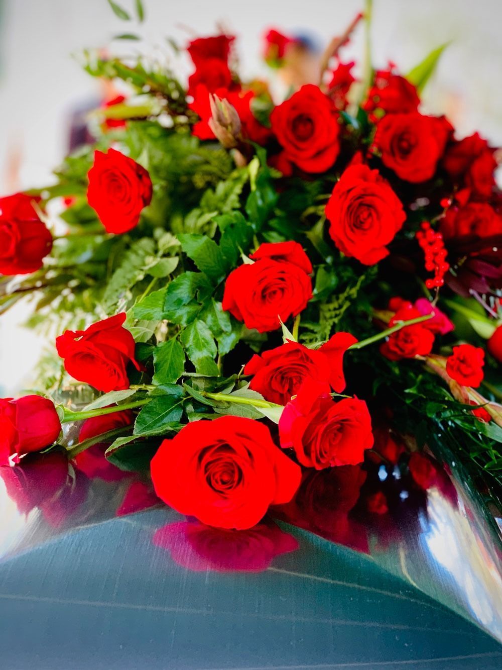 Bouquet of red roses and greenery wrapped in blue paper