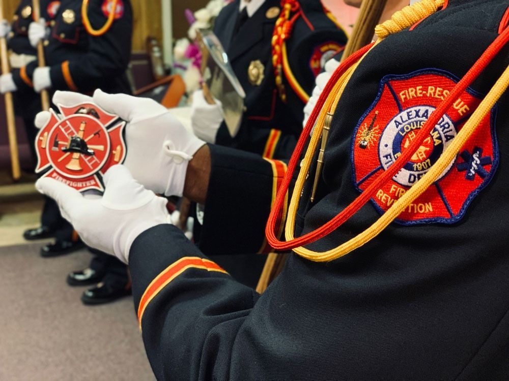 Firefighters in dress uniforms holding a ceremonial badge medallion