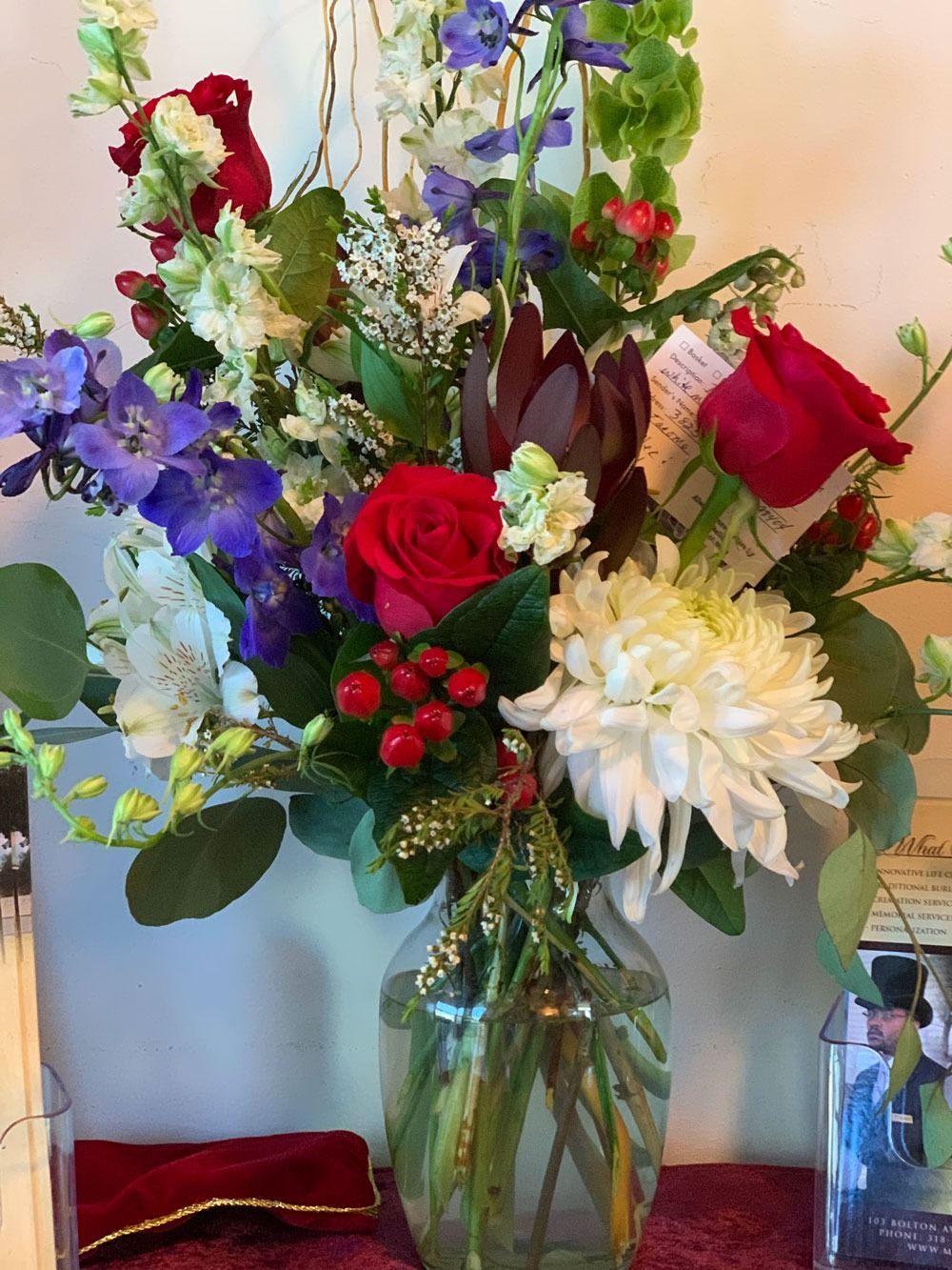 Bouquet of red, white, and purple flowers in a glass vase on a table