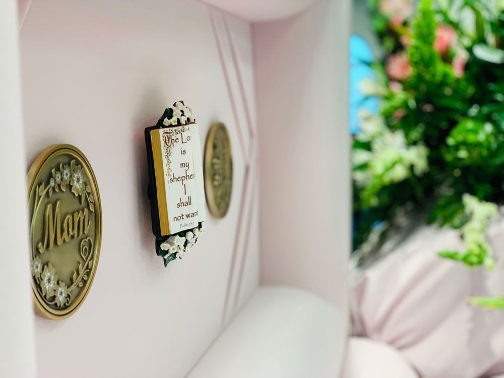 Pink wall with decorative gold signs and a small framed quote, beside a bright window with greenery.