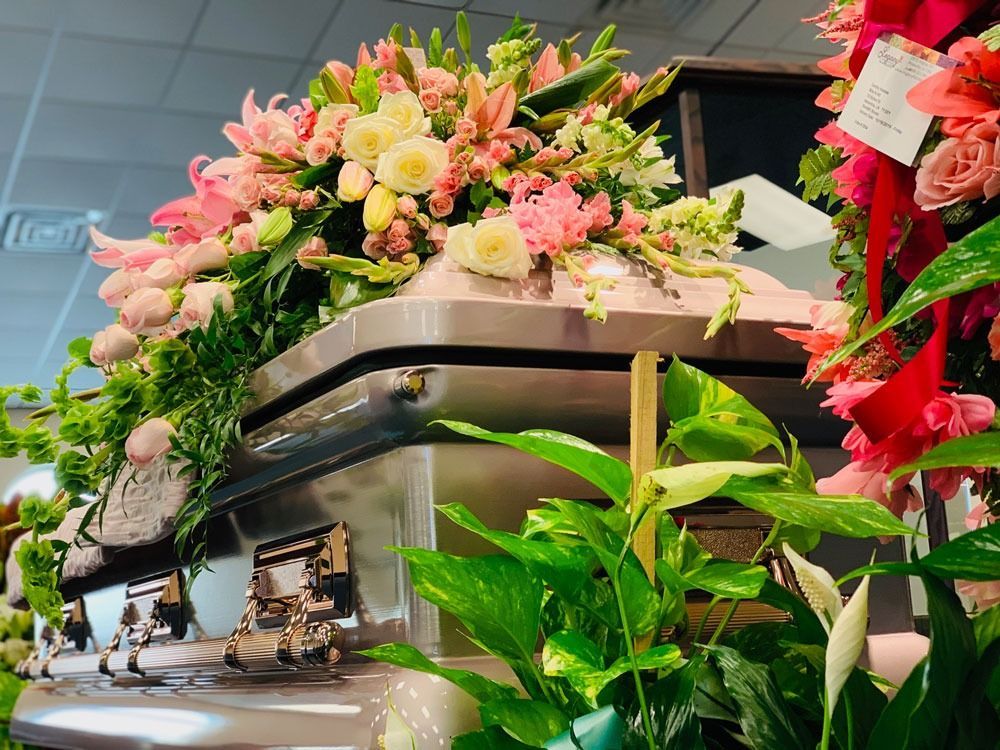 Floral arrangement atop a buffet table with pink and cream flowers and greenery, indoors