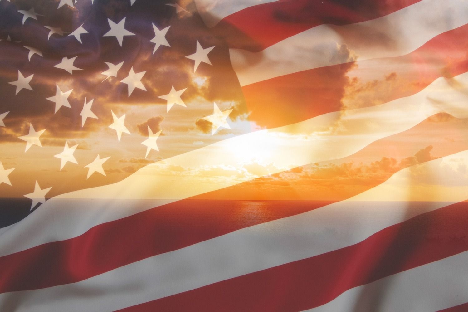 American flag waving at sunset with bright sunlight behind the stars and stripes