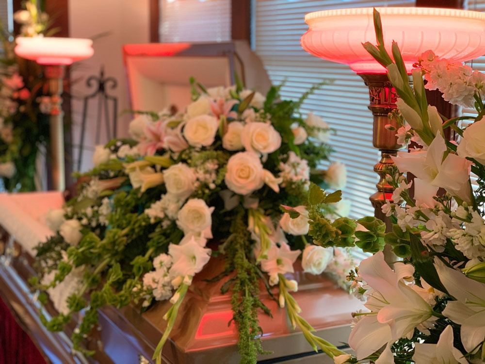 Floral arrangement with white roses and pink lighting on a table indoors