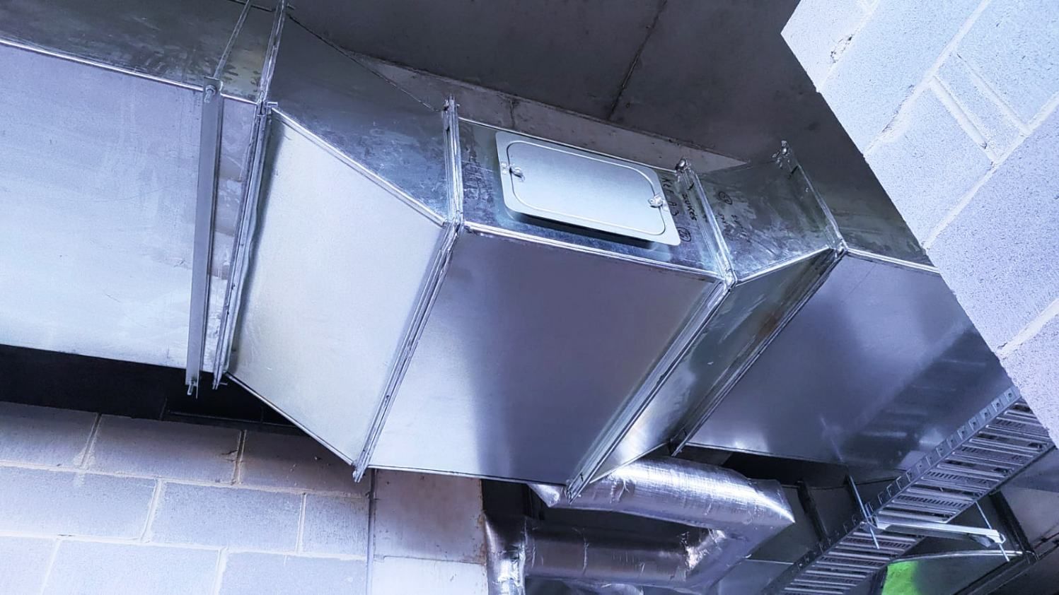 A Metal Pipe is Hanging From the Ceiling of a Building — Accurate Fitout Solutions In Wetherill Park, NSW