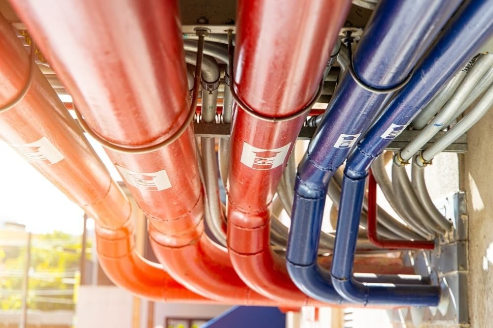 A Bunch of Red and Blue Pipes Hanging From the Ceiling of a Building — Accurate Fitout Solutions In Wetherill Park, NSW