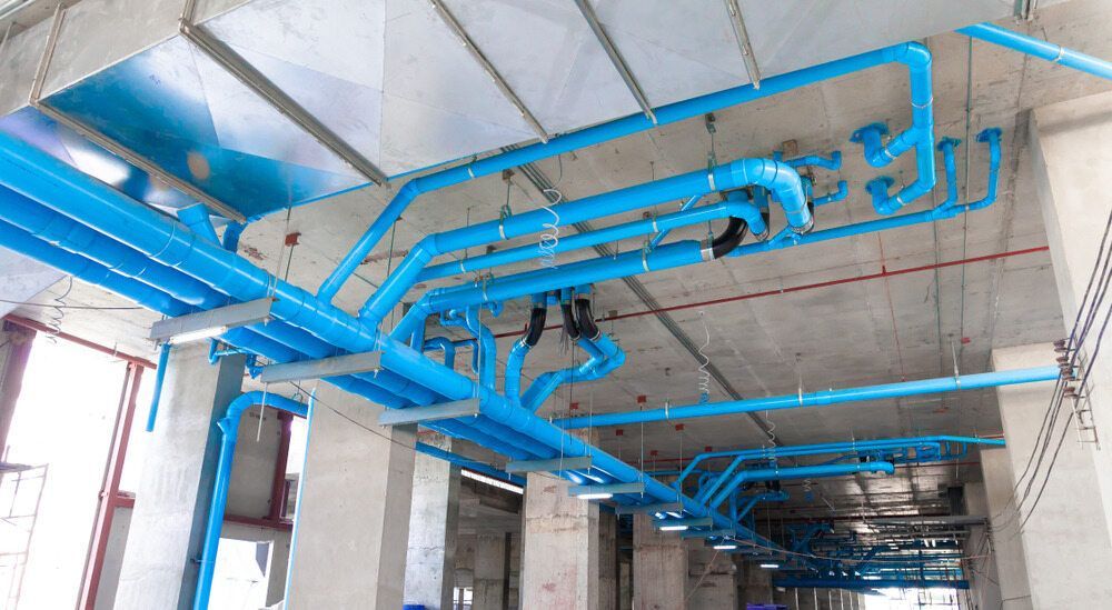 A Bunch of Blue Pipes Are Hanging From the Ceiling of a Building — Accurate Fitout Solutions In Eastern Creek, NSW