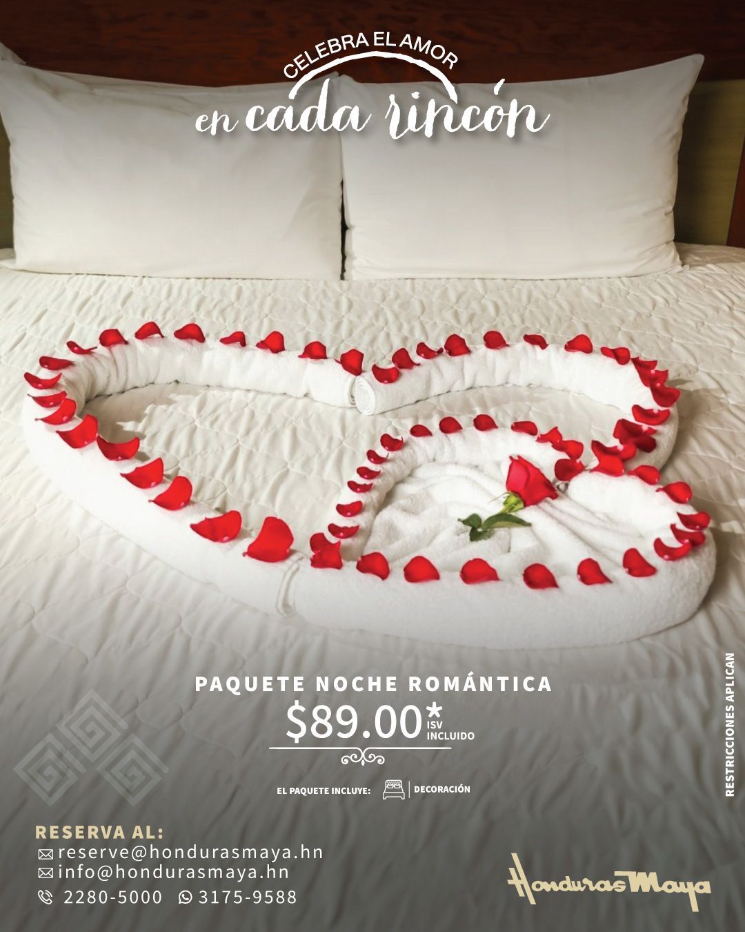 una cama con un corazón hecho de toallas y pétalos de rosa
