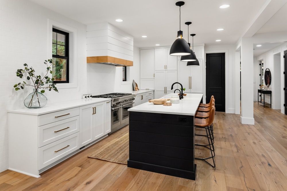 A Kitchen With White Cabinets, Wooden Floors And A Black Island — The Right Kitchen Company in Thirroul, NSW