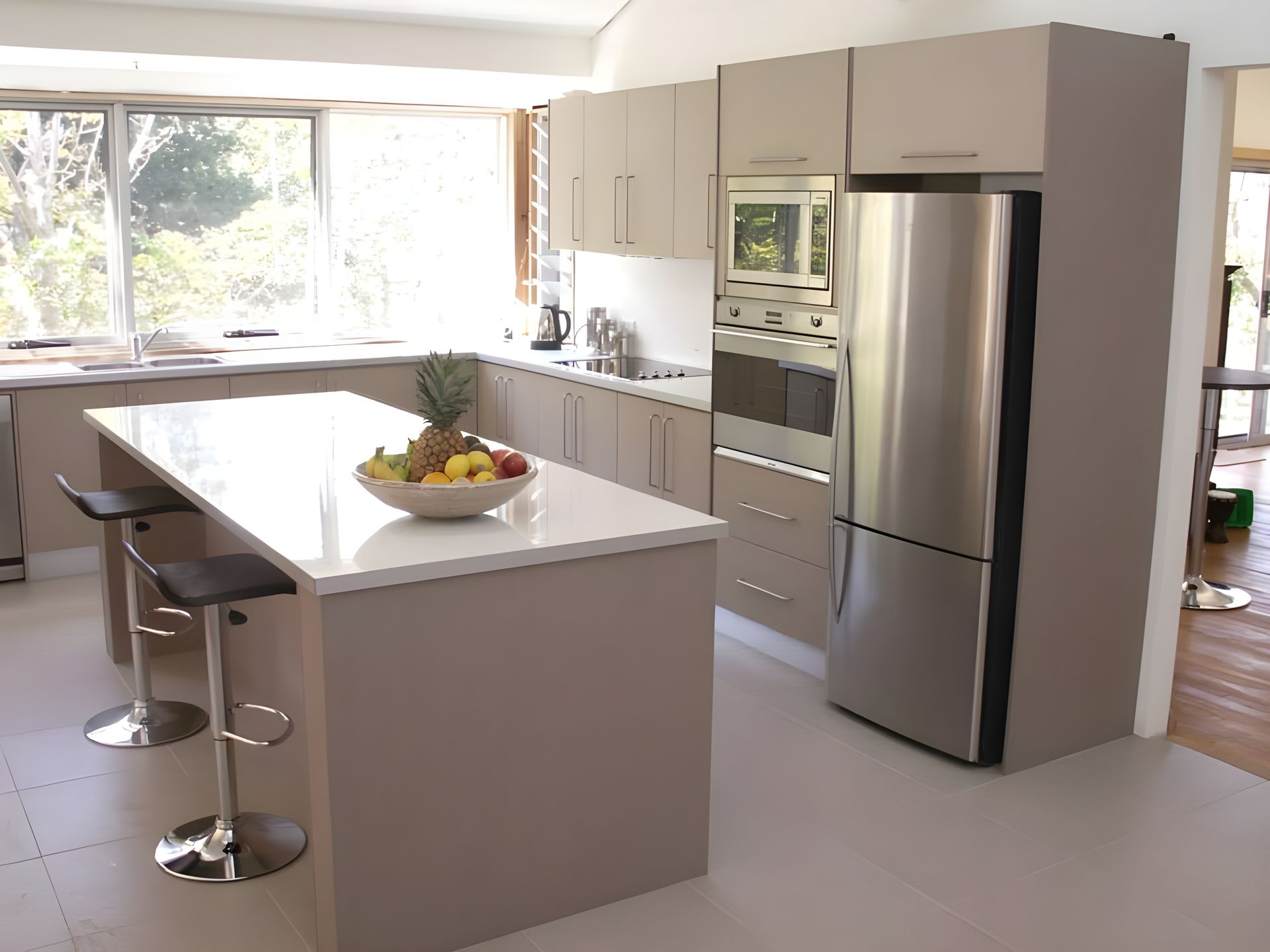 A light filled kitchen with a silver fridge — The Right Kitchen Company In Berkeley, NSW