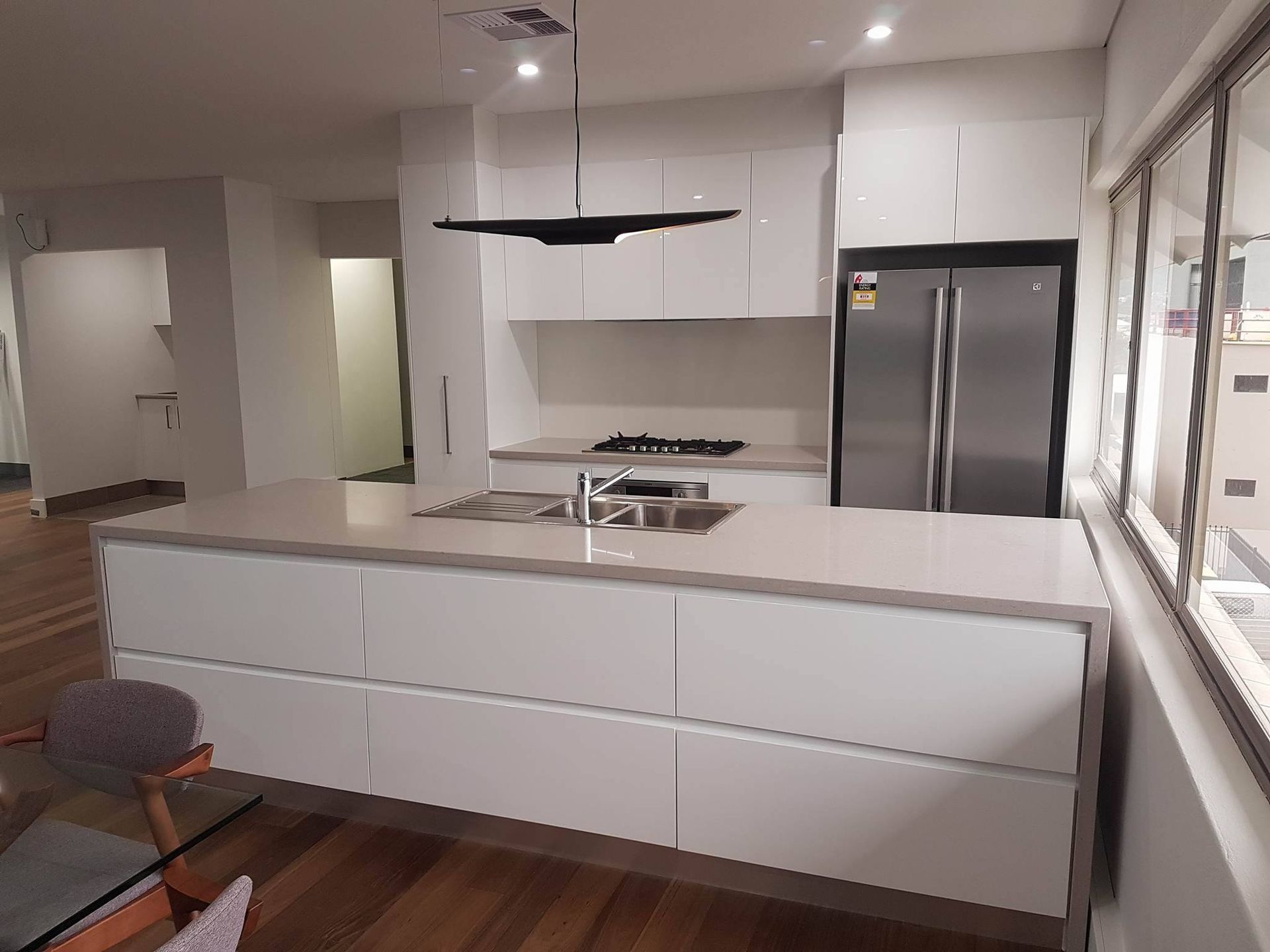 A white kitchen with cabinets on the island bench — The Right Kitchen Company In Berkeley, NSW