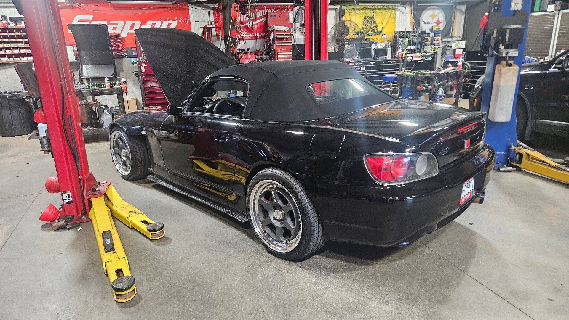 Black convertible sports car on a workshop lift in an auto repair garage, rear view | VP Automotive LLC