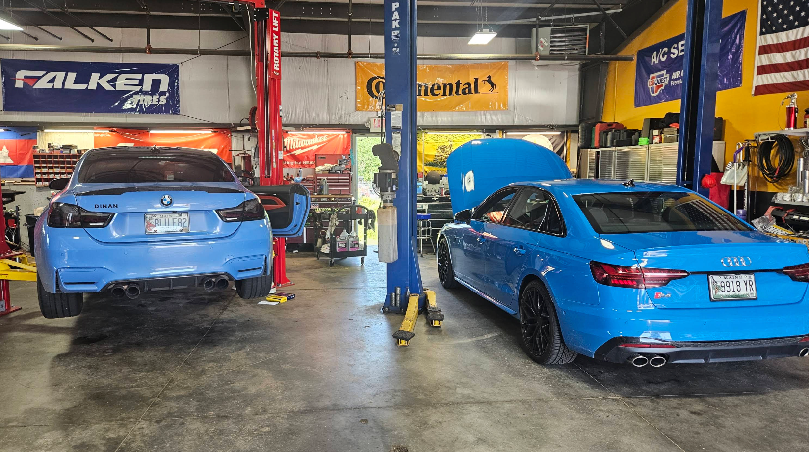 Blue cars in a tire shop garage, one on a lift and one in a service bay. | VP Automotive LLC