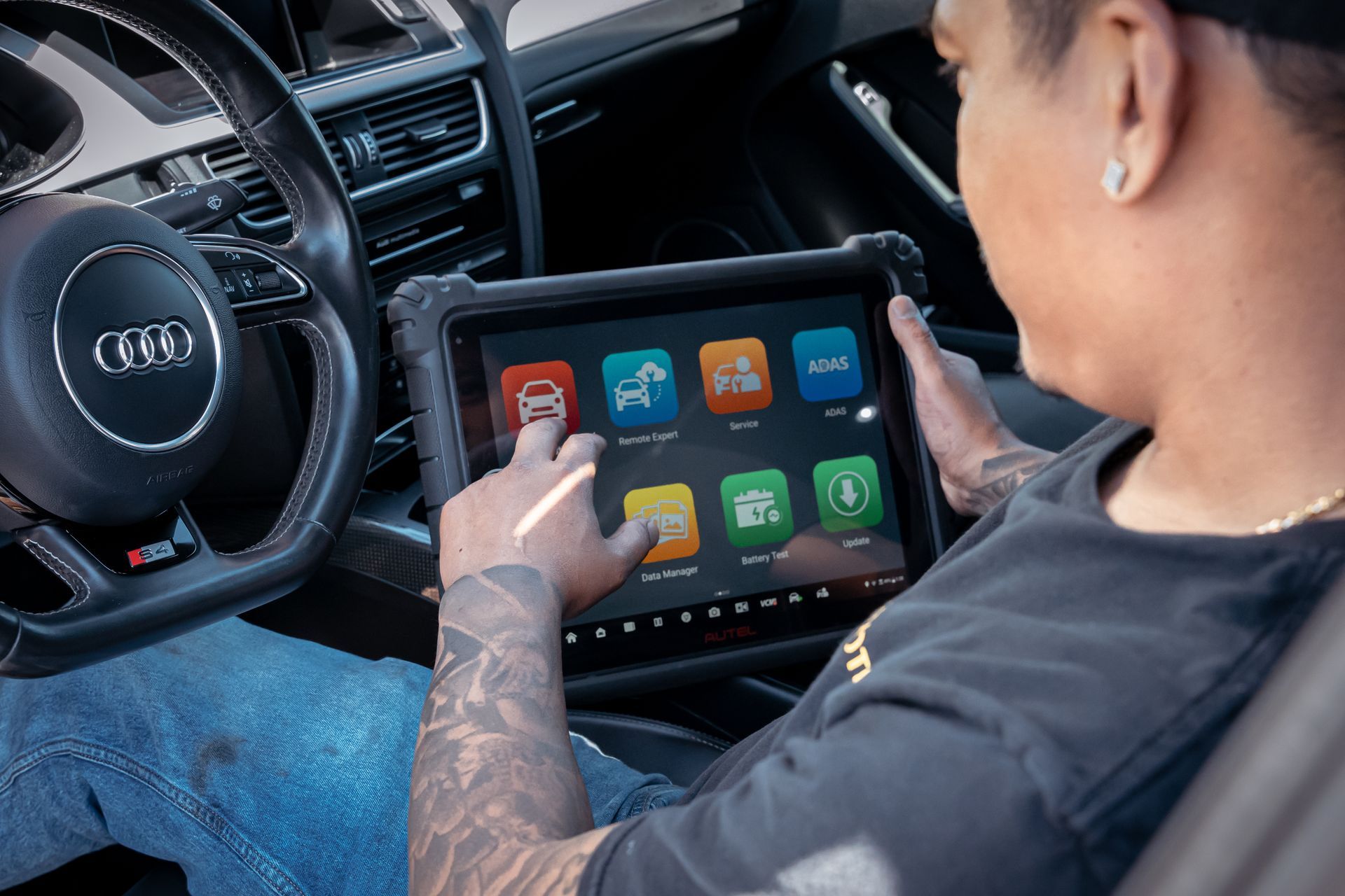 Person using a tablet with app icons inside an Audi car's front seat | VP Automotive LLC