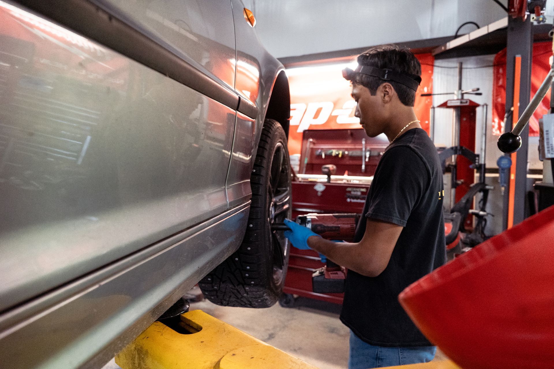 Mechanic inspecting a car on a lift in an auto repair shop | VP Automotive LLC