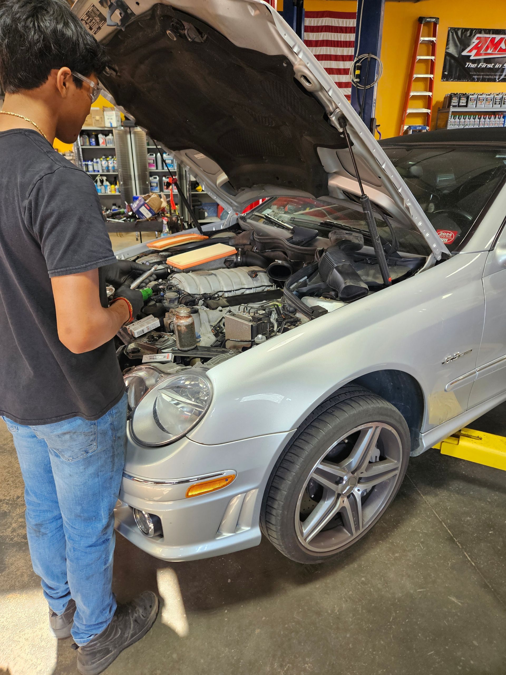 Mechanic inspecting engine bay of a silver sports car with hood open in a garage | VP Automotive LLC