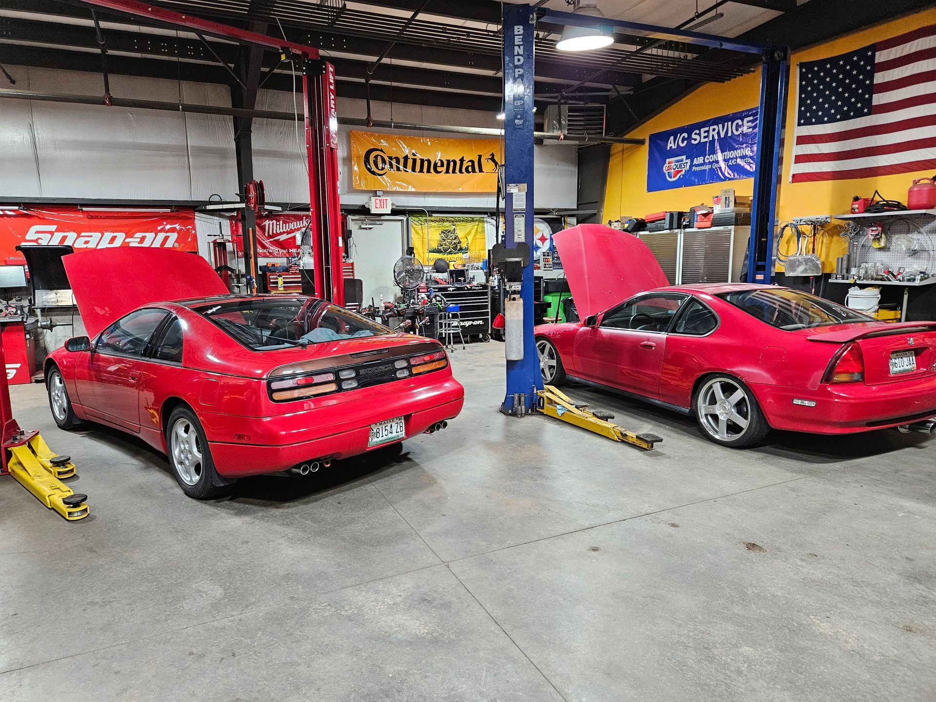 Two red sports cars with hoods open in an auto shop garage | VP Automotive LLC