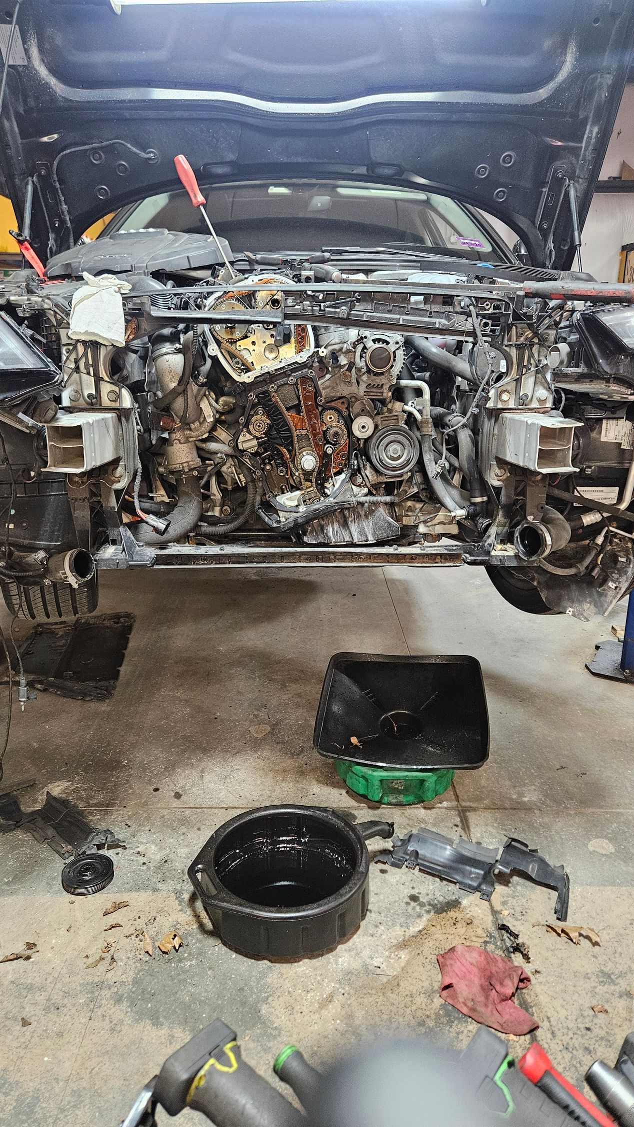 Car engine bay stripped for repair, with tools and parts scattered on the garage floor | VP Automotive LLC