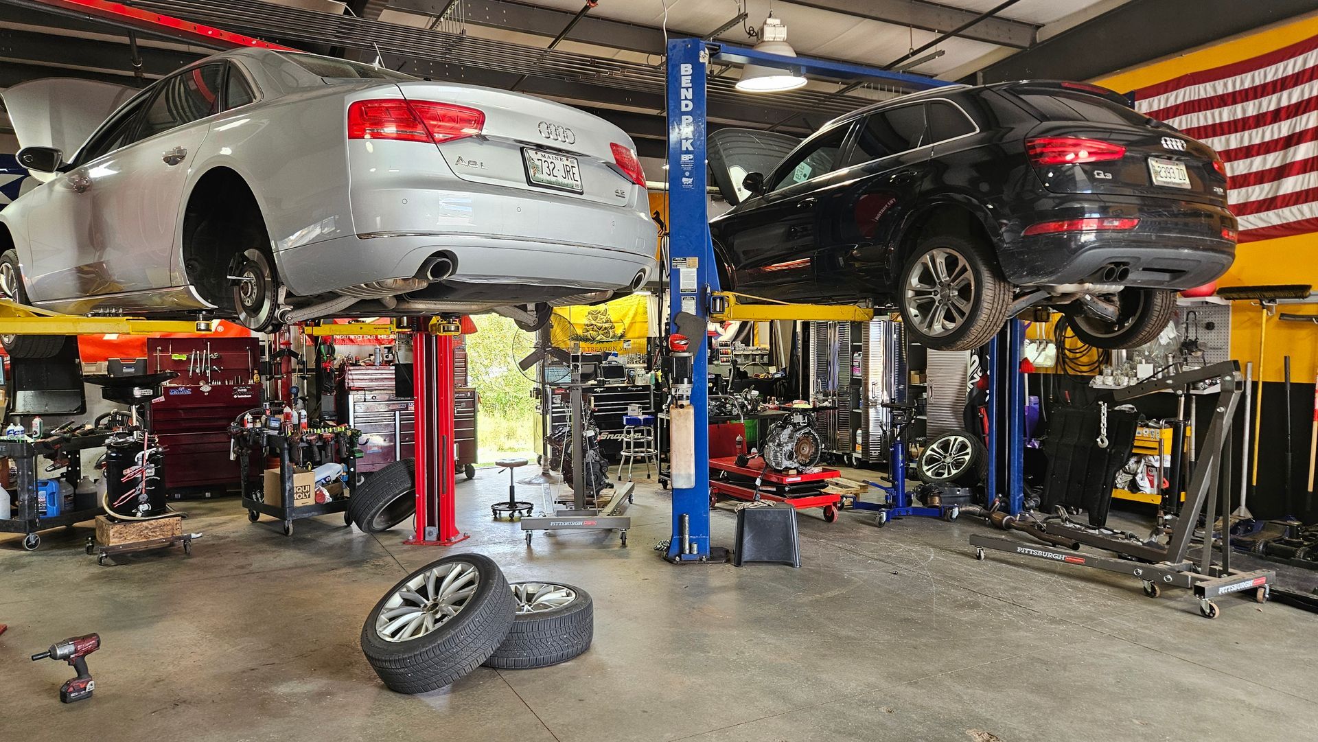 Two cars lifted on hydraulic lifts in an auto repair shop | VP Automotive LLC