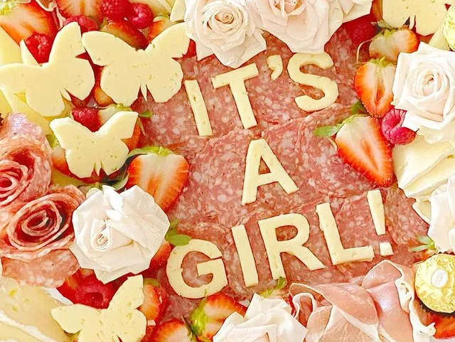 A tray of food with the words `` it 's a girl '' written on it.