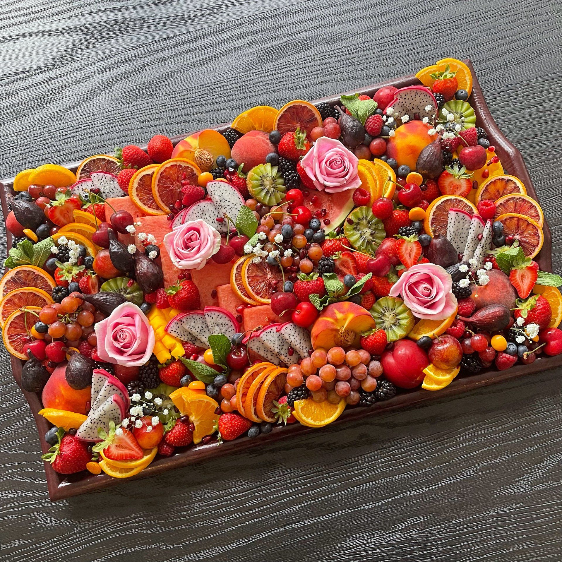 A large tray filled with fruit and flowers on a table.