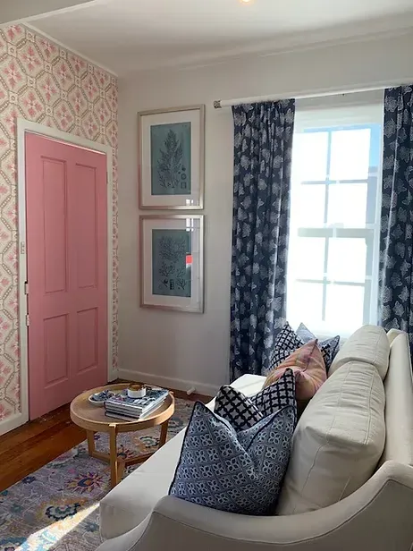 A living room with a white couch and a pink door
