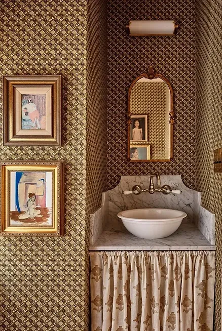 A bathroom with a sink, mirror and paintings on the wall