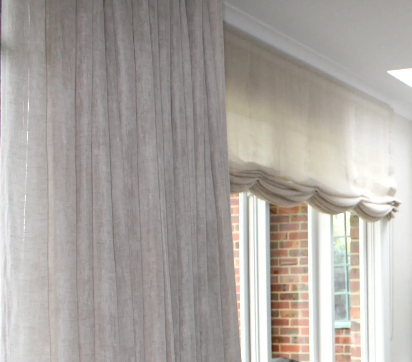 A room with a brick wall and white curtains
