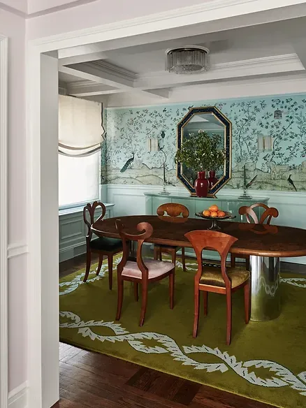 A dining room with a table and chairs and a green rug