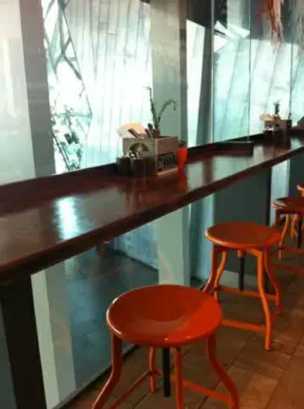 A long wooden table with orange stools in front of it