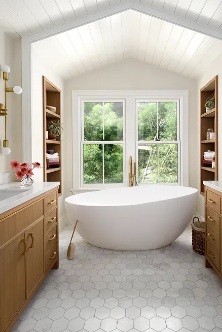 A bathroom with a tub, sink, mirror and window.