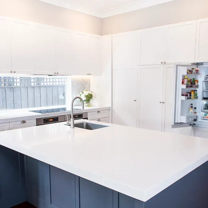 A kitchen with white cabinets, a sink, and a refrigerator.